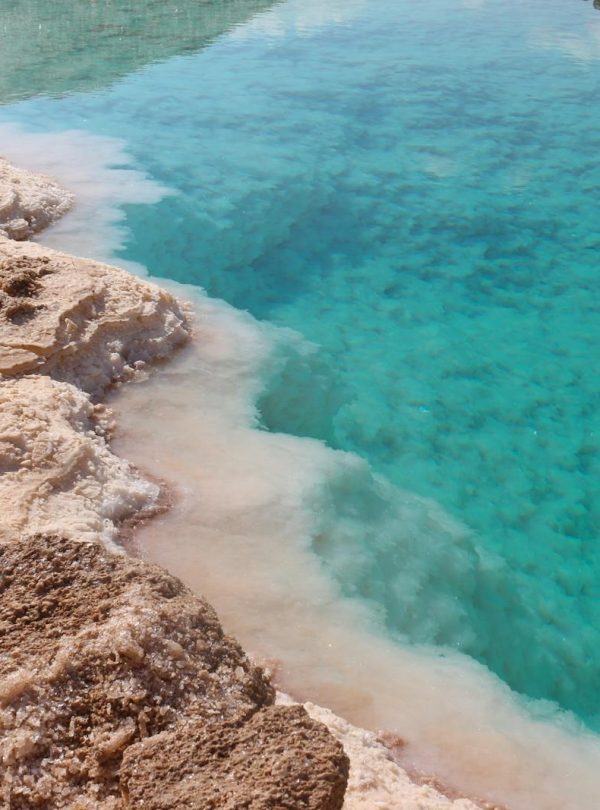 Stunning view of a turquoise salt lake surrounded by rocky desert terrain, a natural marvel.