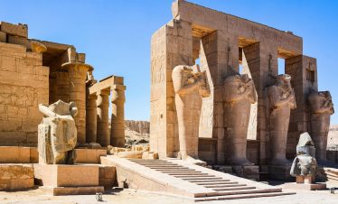 Explore the ancient ruins of Medinet Habu Temple in Egypt, showcasing impressive stone statues and columns.